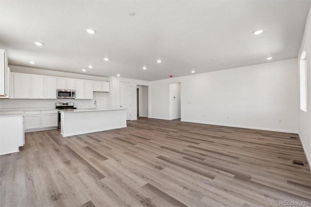 unfurnished living room featuring recessed lighting, visible vents, and a sink
