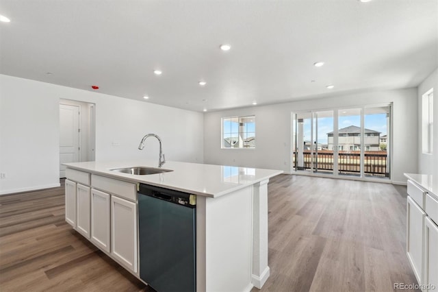 kitchen featuring dishwasher, a sink, light wood finished floors, and light countertops