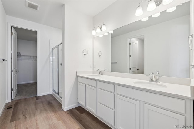 full bathroom with wood finished floors, visible vents, a sink, and a stall shower