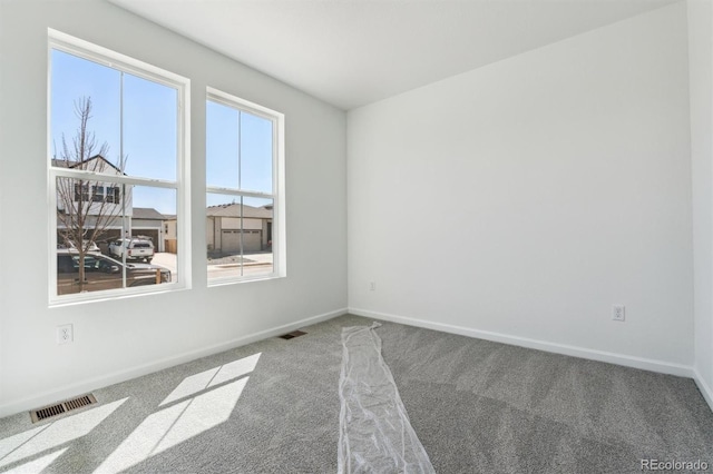 carpeted empty room featuring baseboards and visible vents