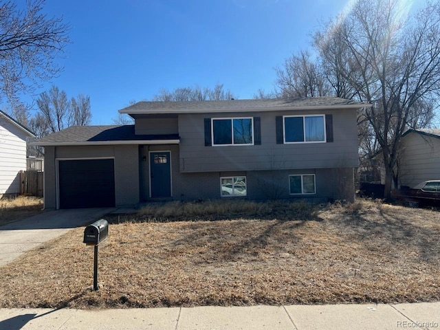 split level home with driveway, brick siding, and an attached garage