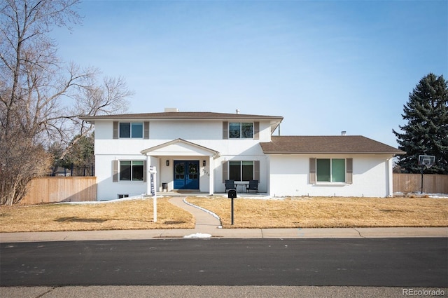 traditional home featuring french doors, fence, and stucco siding