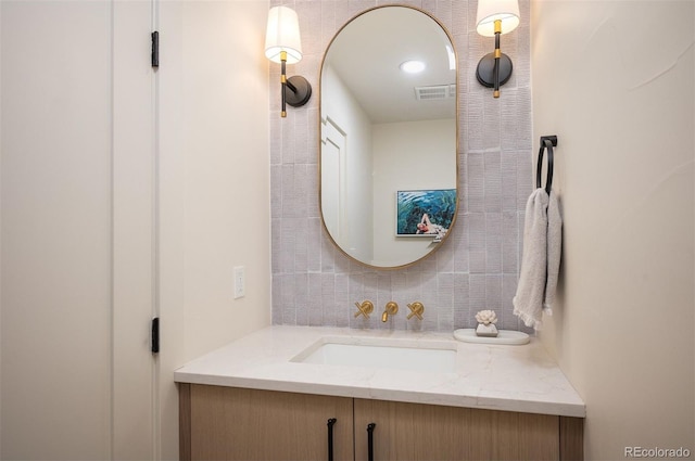 bathroom with visible vents, vanity, and decorative backsplash