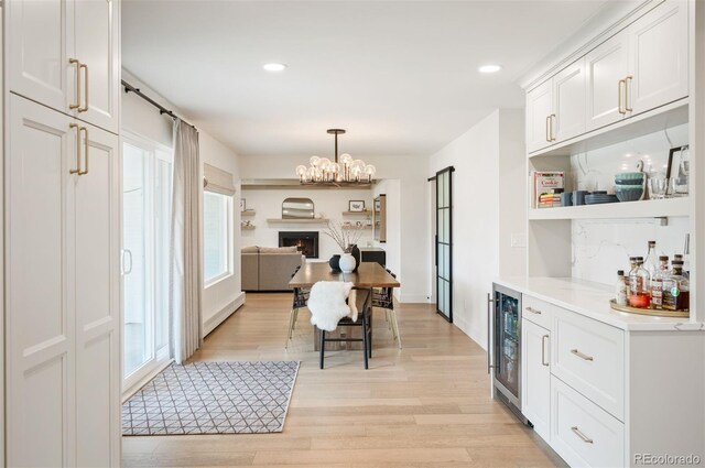 dining space with wine cooler, a notable chandelier, light wood finished floors, and recessed lighting