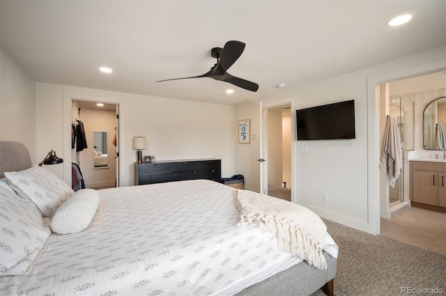 bedroom with baseboards, connected bathroom, light colored carpet, a spacious closet, and recessed lighting