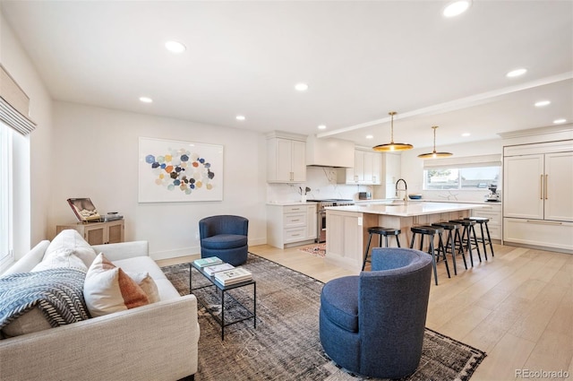 living room featuring baseboards, recessed lighting, and light wood-style floors