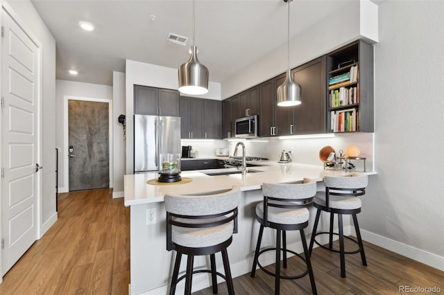 kitchen featuring dark brown cabinetry, stainless steel appliances, kitchen peninsula, and a breakfast bar