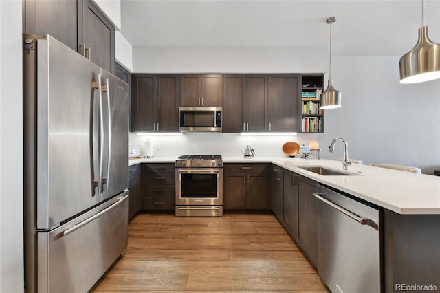 kitchen with sink, appliances with stainless steel finishes, hanging light fixtures, dark brown cabinets, and kitchen peninsula