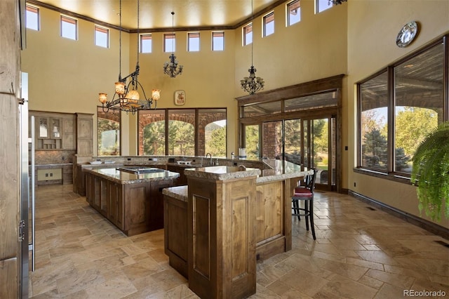 kitchen featuring light stone countertops, a center island, hanging light fixtures, and a healthy amount of sunlight