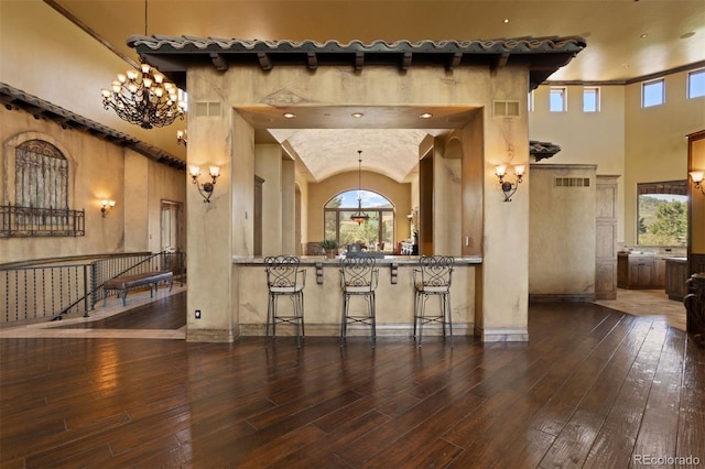 kitchen with a kitchen bar, a towering ceiling, and dark wood-type flooring