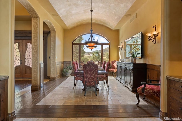 dining room featuring hardwood / wood-style floors, a healthy amount of sunlight, lofted ceiling, and french doors