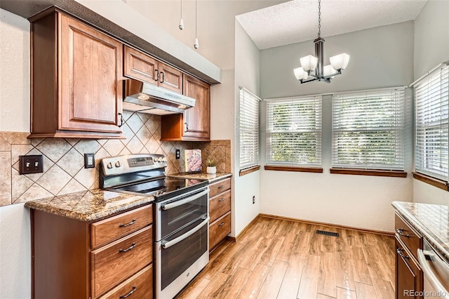 6367 Xavier St, Arvada, CO 80003 - kitchen featuring appliances with stainless steel finishes, under cabinet range hood, a chandelier, light wood-style flooring, and backsplash