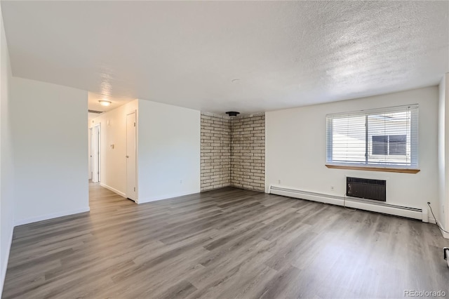 unfurnished living room with baseboards, brick wall, wood finished floors, a textured ceiling, and a baseboard heating unit