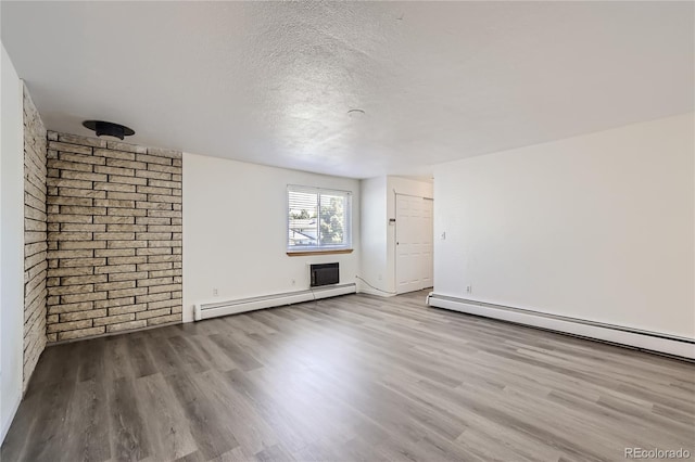 unfurnished room featuring a textured ceiling, baseboard heating, and wood finished floors