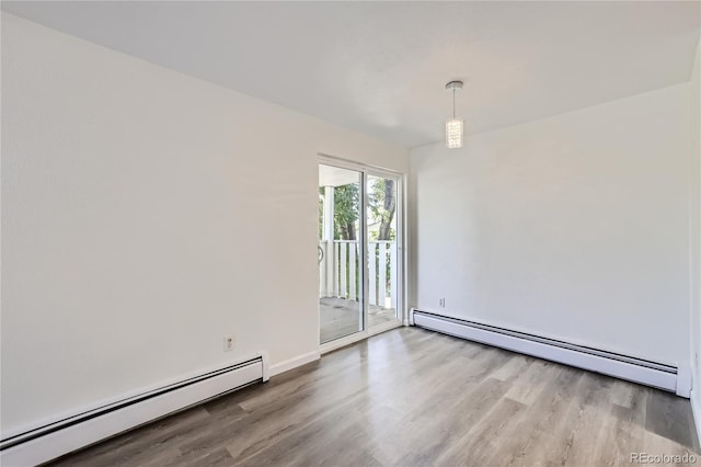 empty room with a baseboard heating unit and wood finished floors