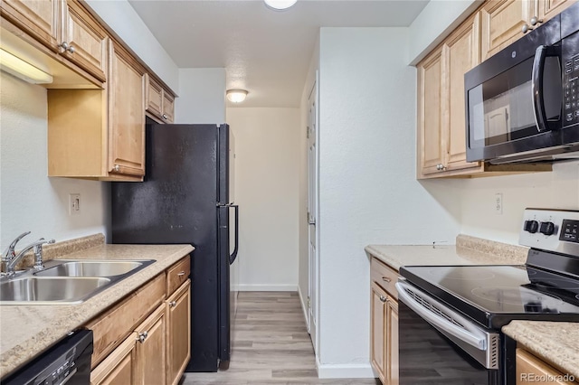 kitchen featuring light brown cabinets, a sink, light countertops, black appliances, and light wood finished floors