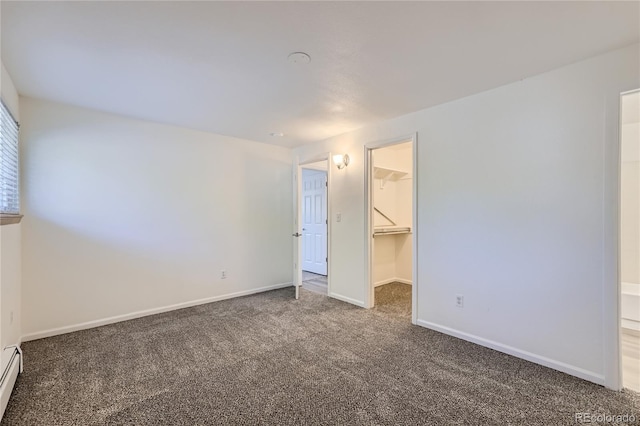 unfurnished bedroom with a baseboard radiator, carpet flooring, baseboards, a spacious closet, and a closet