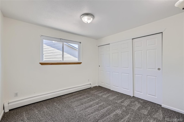 unfurnished bedroom with baseboards, dark carpet, baseboard heating, and a closet