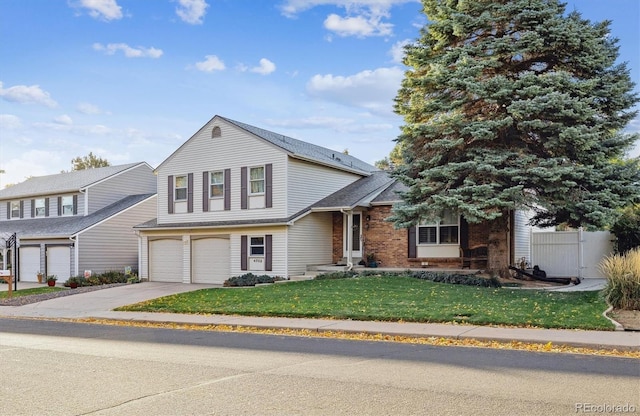 tri-level home with fence, concrete driveway, a front lawn, a garage, and brick siding