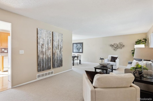 living area with baseboards, carpet, visible vents, and a textured ceiling