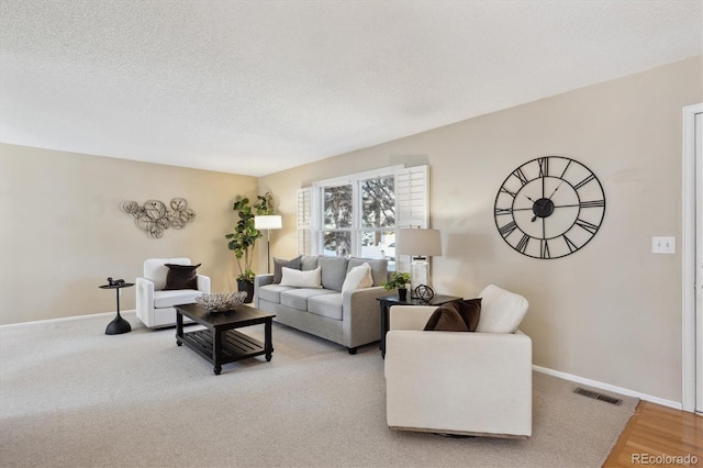 living area featuring visible vents, baseboards, and a textured ceiling