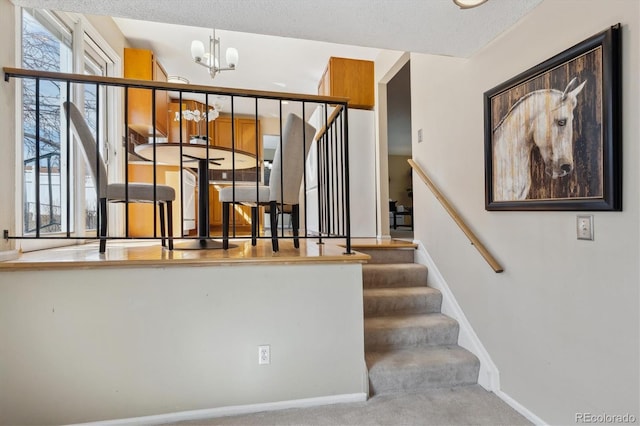 stairs featuring a wealth of natural light, a notable chandelier, baseboards, and carpet