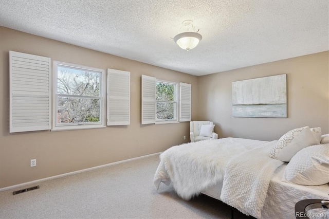 bedroom featuring baseboards, carpet floors, a textured ceiling, and visible vents