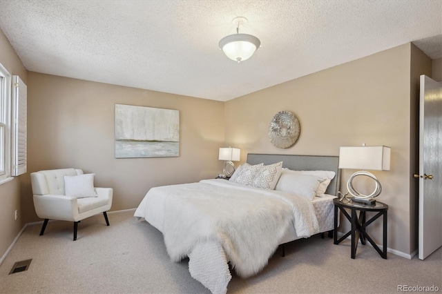 carpeted bedroom with visible vents, a textured ceiling, and baseboards