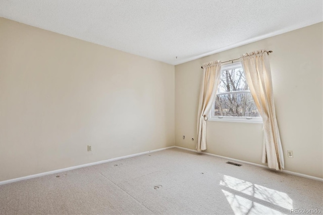 carpeted spare room featuring visible vents, baseboards, and a textured ceiling