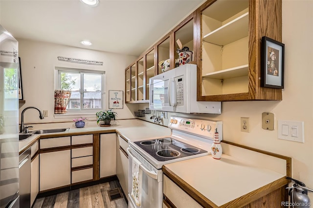 kitchen with wood finished floors, a sink, light countertops, recessed lighting, and white appliances