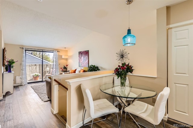 dining room with wood finished floors and lofted ceiling