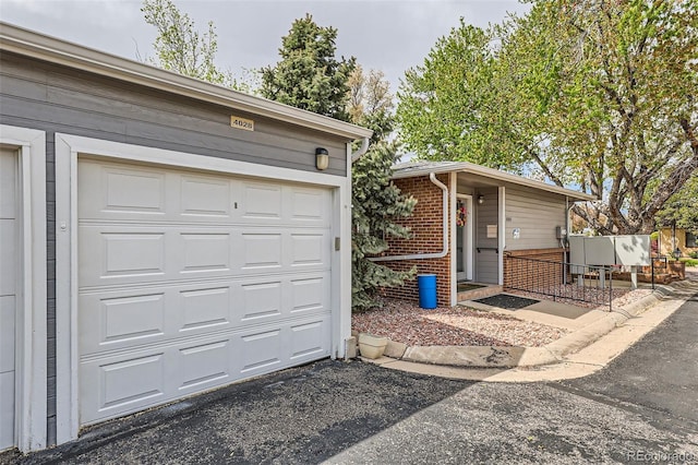 view of front of property featuring a garage, aphalt driveway, and brick siding