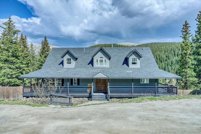 234 Carroll Ln, Breckenridge, CO 80424 - farmhouse-style home with a porch, a wooded view, and a shingled roof