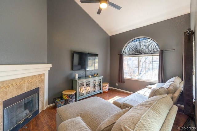 living area with baseboards, ceiling fan, wood finished floors, a fireplace, and high vaulted ceiling