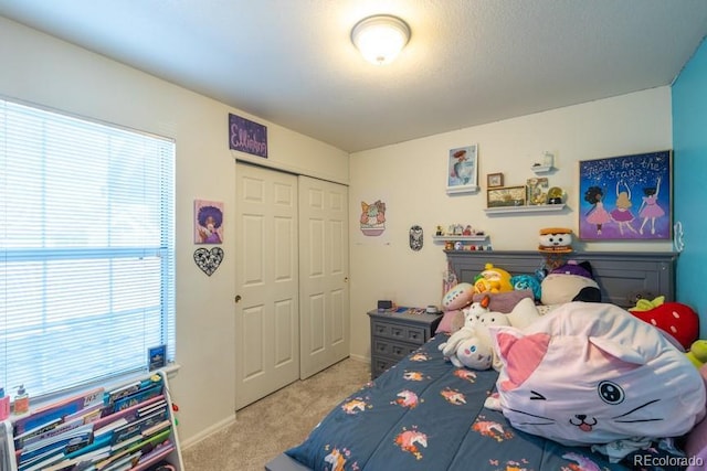 carpeted bedroom featuring baseboards and a closet