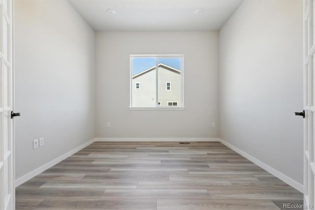 unfurnished room featuring baseboards and light wood-style floors