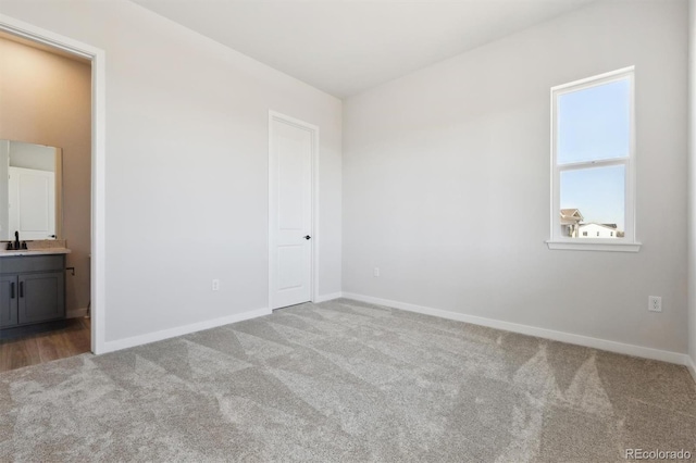 unfurnished bedroom featuring carpet flooring, baseboards, and a sink