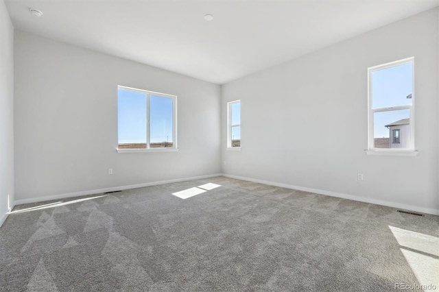 carpeted spare room featuring visible vents and baseboards