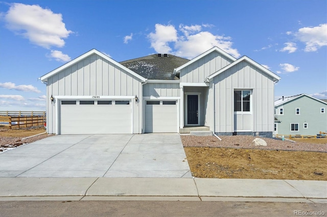 modern inspired farmhouse with board and batten siding, concrete driveway, a garage, and fence
