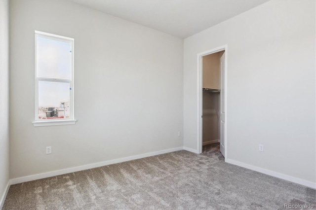 unfurnished bedroom featuring baseboards, carpet flooring, a closet, and a spacious closet