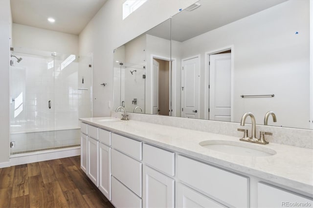full bathroom featuring a sink, a shower stall, and wood finished floors