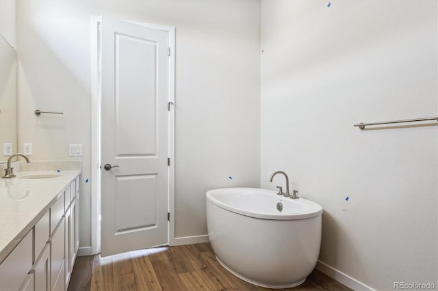 bathroom featuring vanity, a freestanding tub, baseboards, and wood finished floors