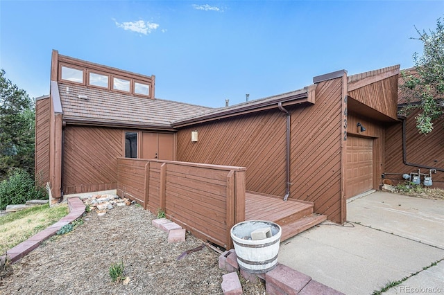 rear view of house featuring concrete driveway and an attached garage