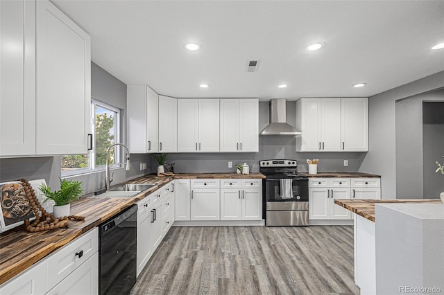 kitchen featuring wall chimney range hood, sink, light hardwood / wood-style floors, stainless steel electric range oven, and dishwasher