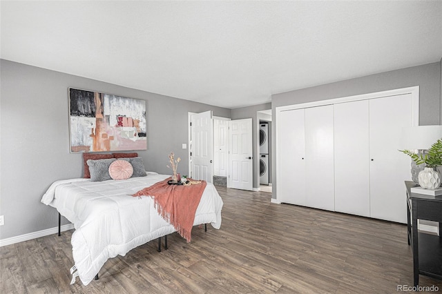 bedroom with wood-type flooring, a closet, and stacked washer and dryer