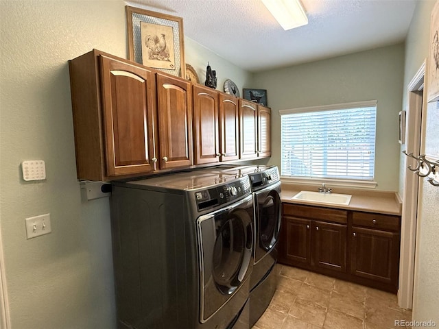 laundry area with cabinets, sink, washing machine and clothes dryer, and a textured ceiling