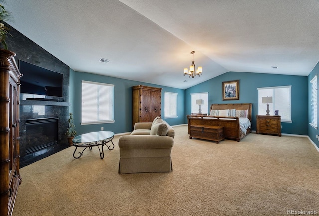 carpeted bedroom with lofted ceiling, a tile fireplace, a textured ceiling, and an inviting chandelier