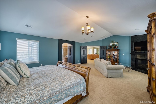 bedroom featuring vaulted ceiling, a large fireplace, light colored carpet, and an inviting chandelier