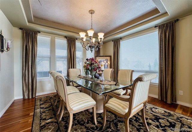 dining space featuring dark wood-style floors, a tray ceiling, and a wealth of natural light