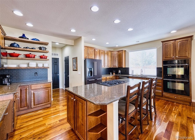 kitchen with stainless steel appliances, light wood-style floors, a sink, and open shelves